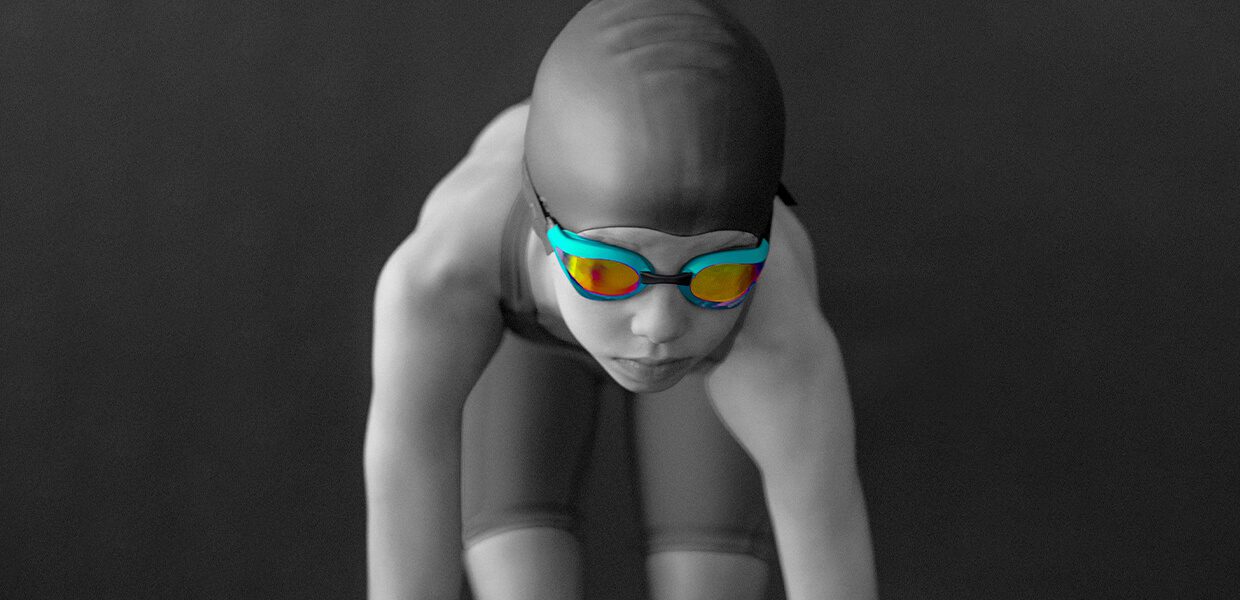 Swimmer in goggles prepares to dive in a monochrome setting with colored lenses.